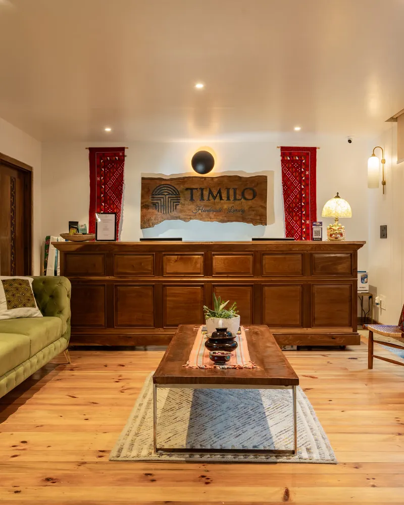 Reception at Timilo — a hand-carved desk under the carved Timilo sign, with a green velvet sofa