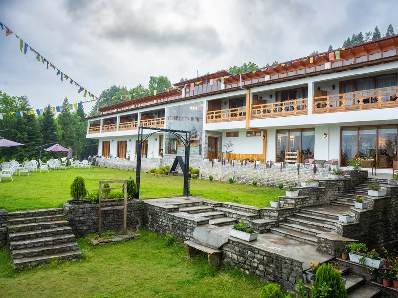The white-gabled house and its lawn, strung with prayer flags, seen from the front