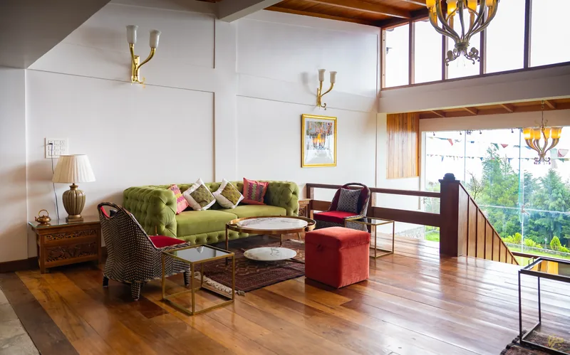 The lounge with a green chesterfield, painted details and a wall of mountain glass